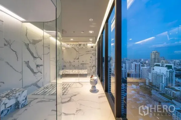 Condominium for rent in Watthana, Bangkok - Luxury marble-clad steam room and spa area with city panorama at dusk.