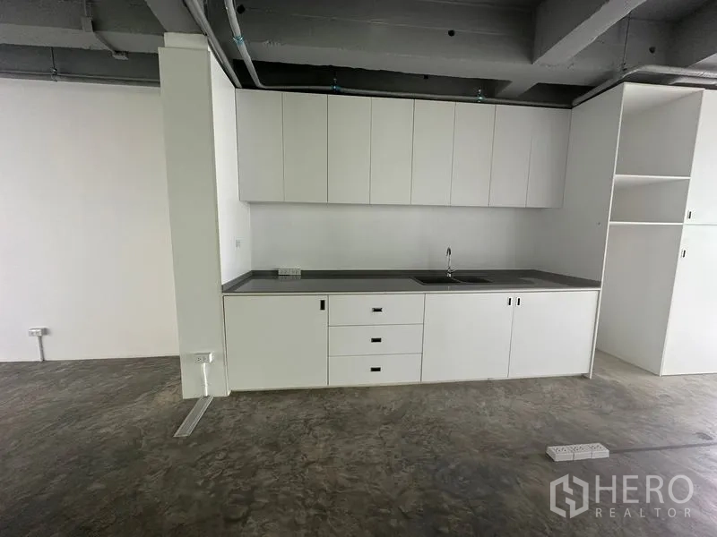 Office Space for rent in Khlong Toei, Bangkok - White office pantry with upper cabinets, drawers and sink on a polished concrete floor.