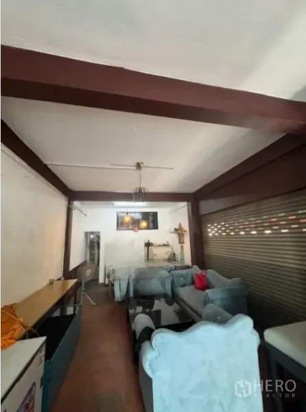 Shophouse for rent in Khlong Toei, Bangkok - Ground-floor shophouse interior with sofas, counter and metal shutter.