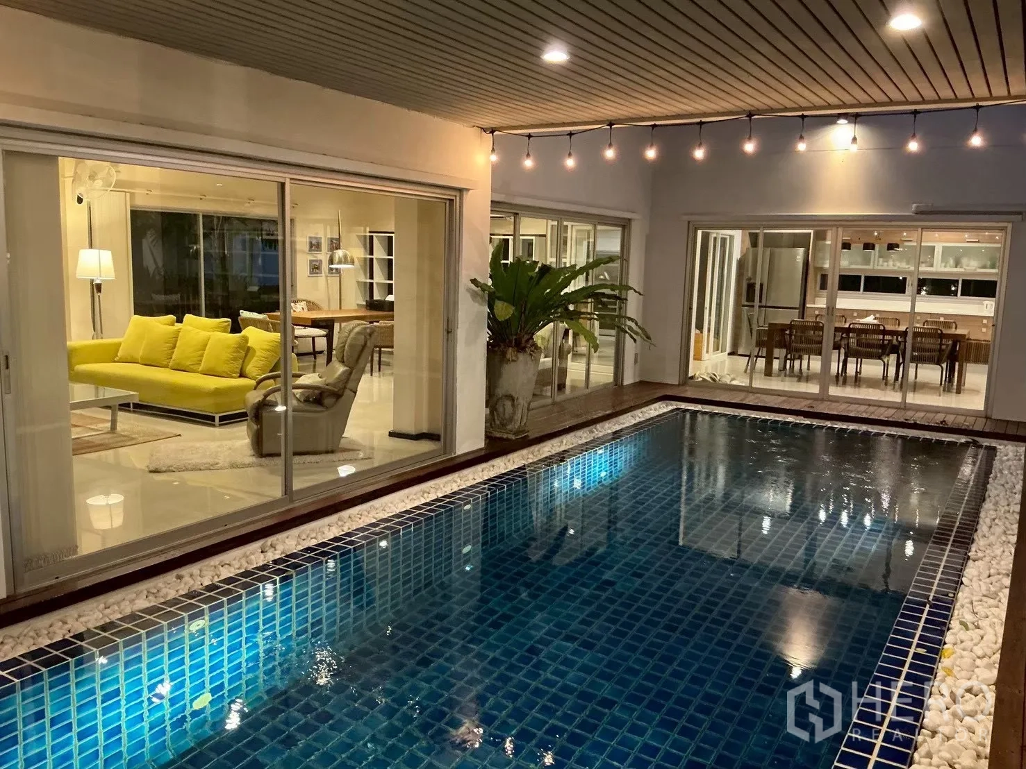 独栋房屋 for sale in Suan Luang, Bangkok - 夜晚的私人泳池，吊灯与玻璃门相映。