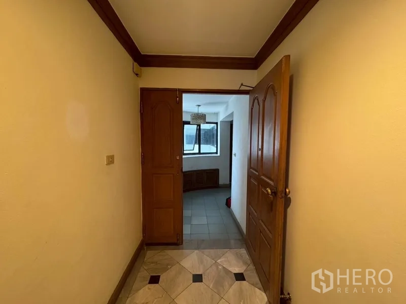 Condominium for rent in Watthana, Bangkok - Entrance hallway with wooden door opening to a tiled foyer.