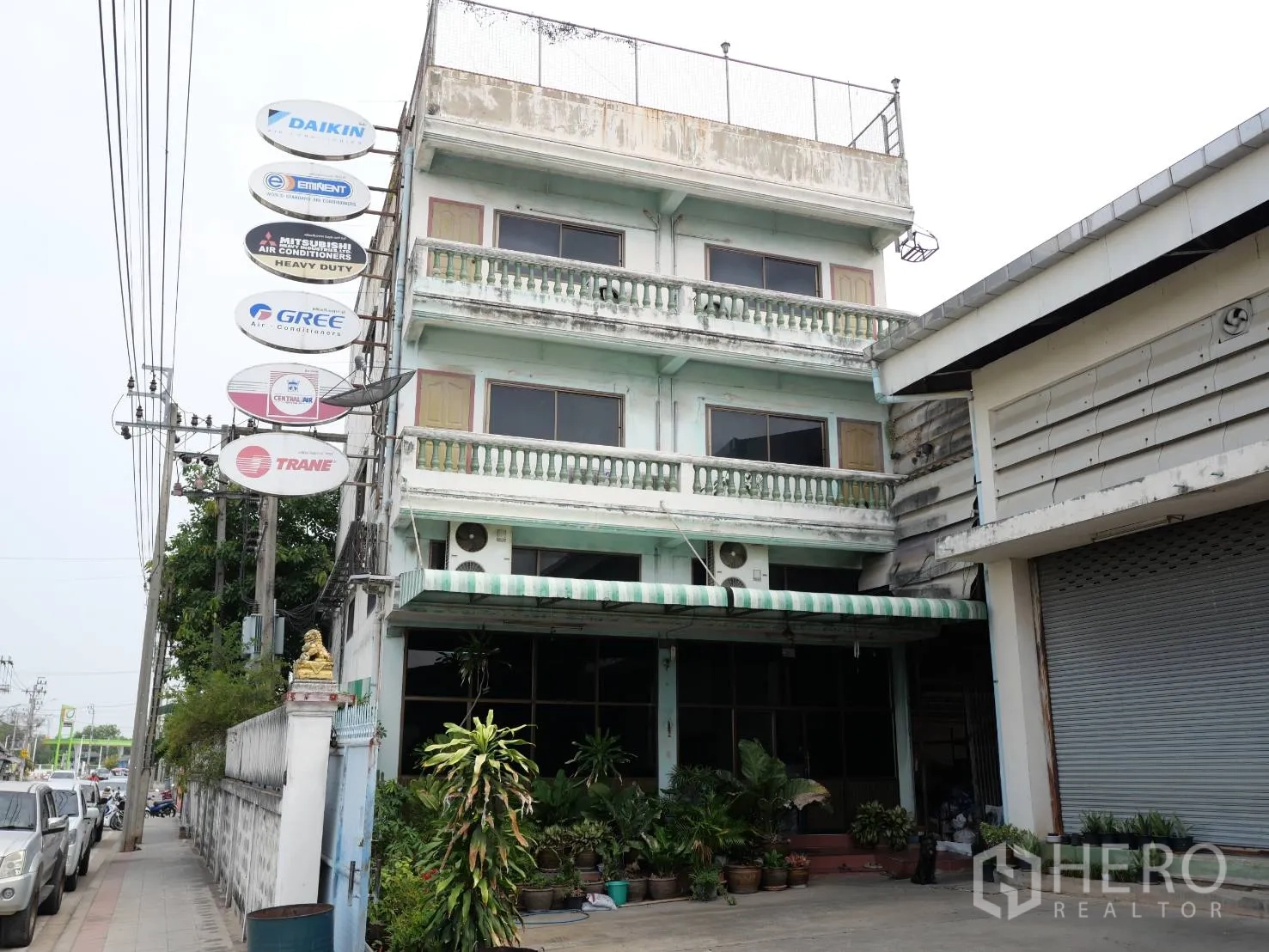 工厂 出租或出售在Bang Khun Thian, Bangkok - 3.5层商业办公楼正立面，带雨棚与卷帘门，紧邻厂房。