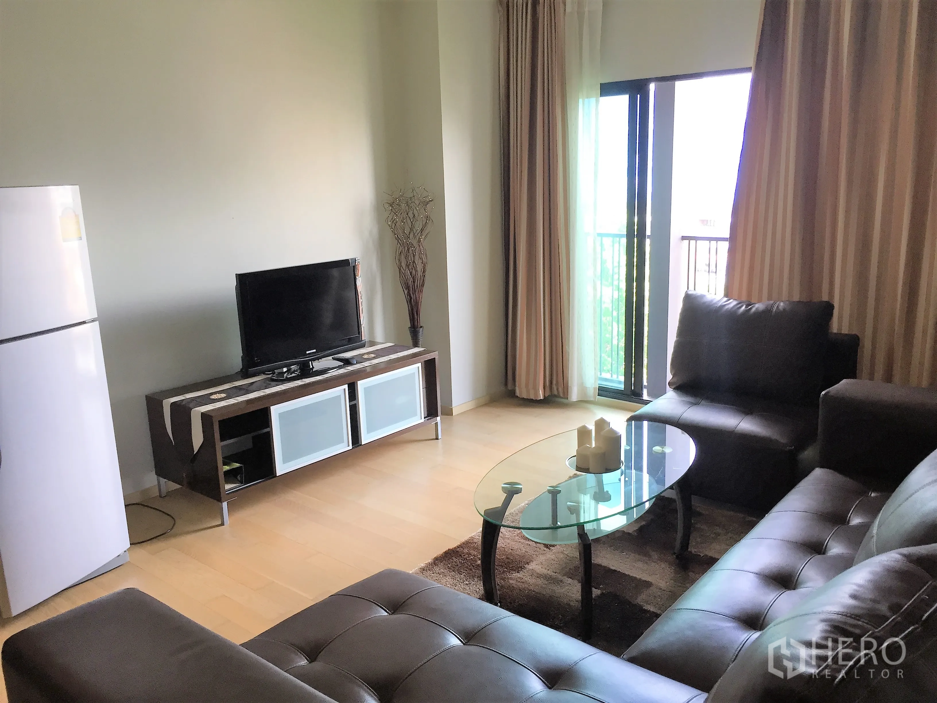 公寓 出租在Watthana, Bangkok - 明亮客厅，电视柜、玻璃茶几、皮沙发并连接阳台。