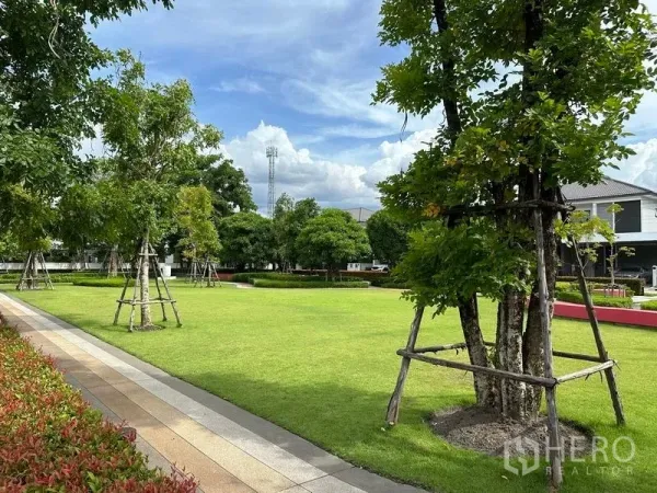 Detached House for sale in Nonthaburi - Lush communal park with open lawn, mature trees and a paved walkway.