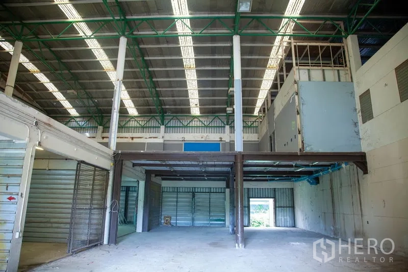 Warehouse for rent in Prawet, Bangkok - Two-level warehouse area featuring steel mezzanine, roller doors and open storage floor.