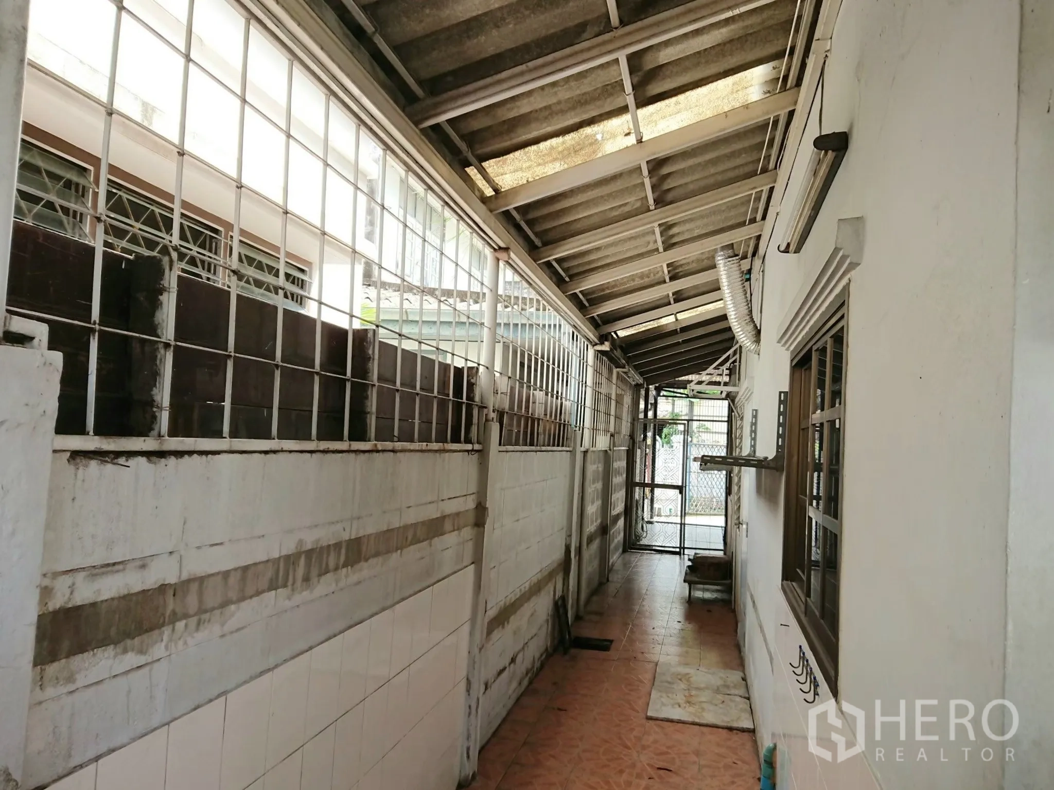 Detached House for sale in Chatuchak, Bangkok - Service corridor with roof cover and security grilles.
