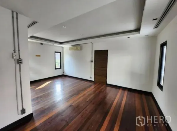 Home Office for rent in Lat Phrao, Bangkok - Spacious office room with polished wood floors, white walls and ceiling lighting with a door to the corridor.