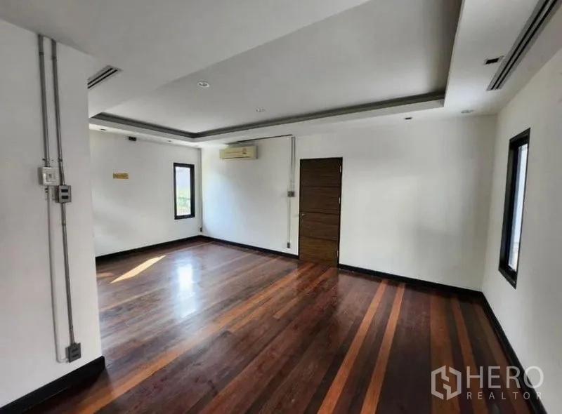 Home Office for rent in Lat Phrao, Bangkok - Spacious office room with polished wood floors, white walls and ceiling lighting with a door to the corridor.