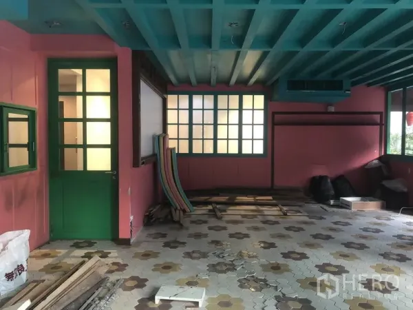 Retail Space for rent in Khlong Toei, Bangkok - Open retail area showing green-framed doors and frosted windows with construction materials on the floor.