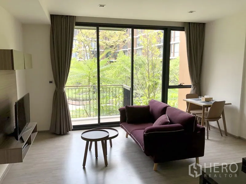 Condominium for rent in Watthana, Bangkok - Bright living room with floor-to-ceiling windows, balcony, and lush garden view at Mori Haus.