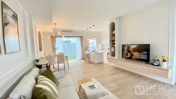 Townhouse for rent in Prawet, Bangkok - Bright open-plan living, dining and kitchen with light wood floors, built-in TV wall and sliding doors to the patio.