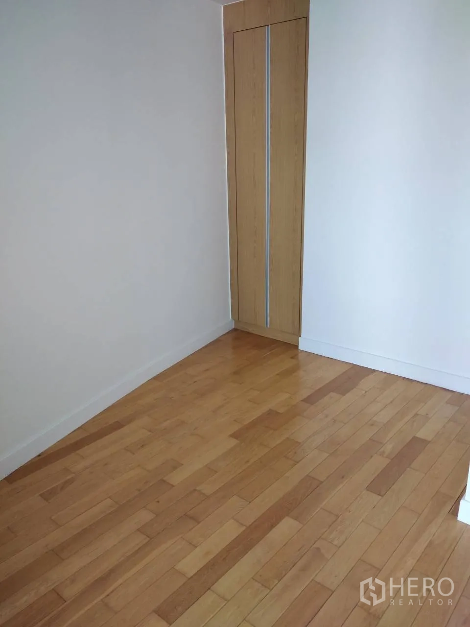 Condominium for rent in Khlong Toei, Bangkok - Empty room with built-in wardrobe and light wood flooring.