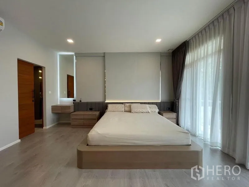 Detached House for rent in Prawet, Bangkok - Spacious master bedroom with king bed, bedside drawers and sliding glass doors to a balcony.