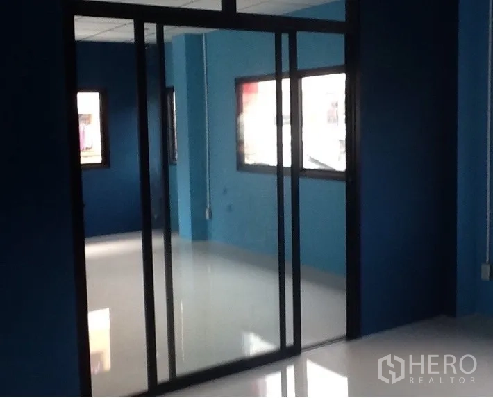 Warehouse for rent in Bang Kapi, Bangkok - Bright blue office space with sliding glass doors and multiple windows.