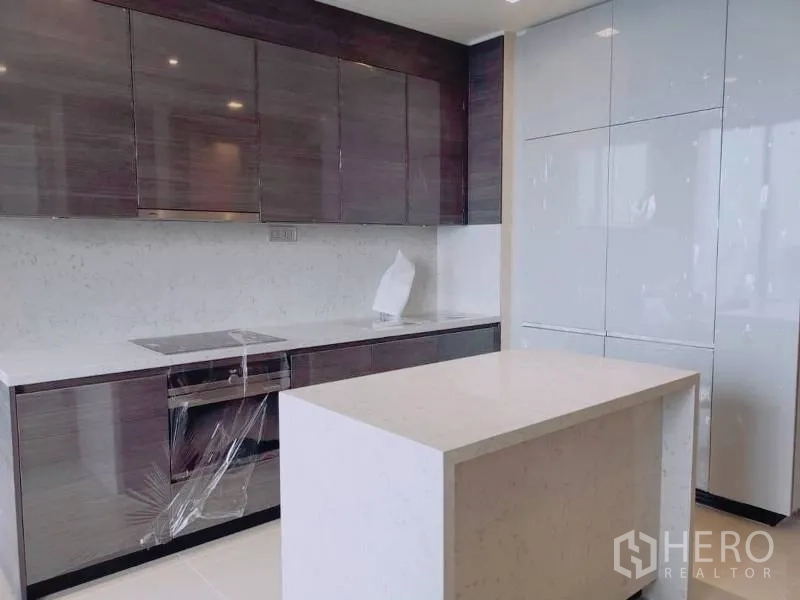Condominium for rent or sale in Watthana, Bangkok - Contemporary kitchen with glossy cabinets, white stone countertops, island and built-in oven.