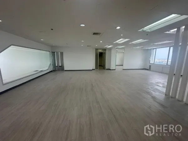Office Space for rent - Expansive office floor with LED ceiling lights, slatted partitions, and large windows overlooking Bangkok.