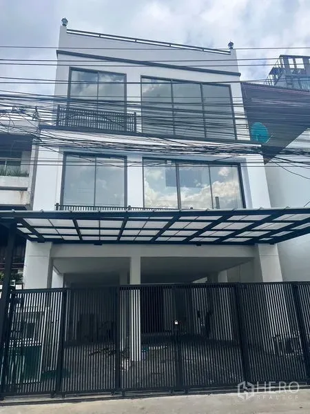 带办公室的家 出租或出售在Watthana, Bangkok - 街景视角：黑色金属围栏与玻璃立面的家办楼。