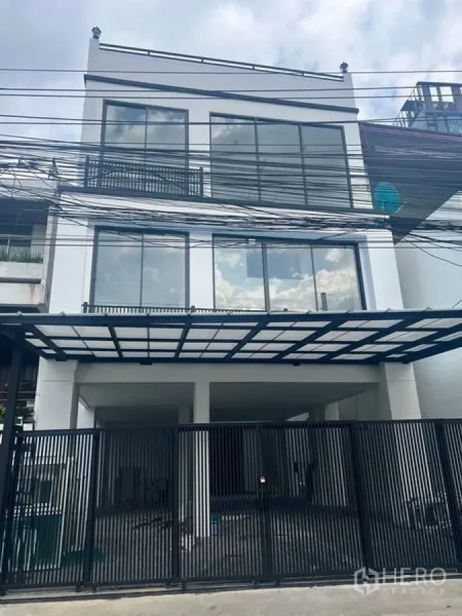 สำนักงานที่บ้าน ให้เช่าหรือขายในWatthana, Bangkok - มุมมองด้านหน้า พร้อมรั้วเหล็กสีดำและฟาซาดกระจกของอาคารโฮมออฟฟิศ