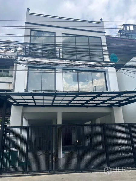 สำนักงานที่บ้าน ให้เช่าหรือขายในWatthana, Bangkok - มุมมองด้านหน้า พร้อมรั้วเหล็กสีดำและฟาซาดกระจกของอาคารโฮมออฟฟิศ