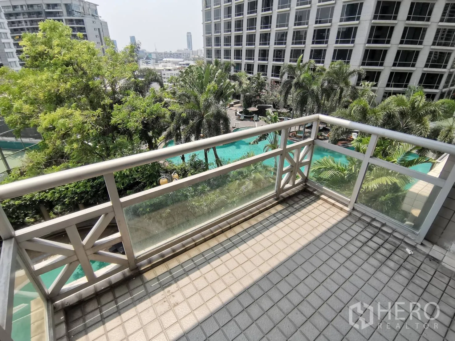 คอนโด ให้เช่าในPathum Wan, Bangkok - ระเบียงมองเห็นสระว่ายน้ำสไตล์รีสอร์ต สวนปาล์ม และอาคารสูงโดยรอบ