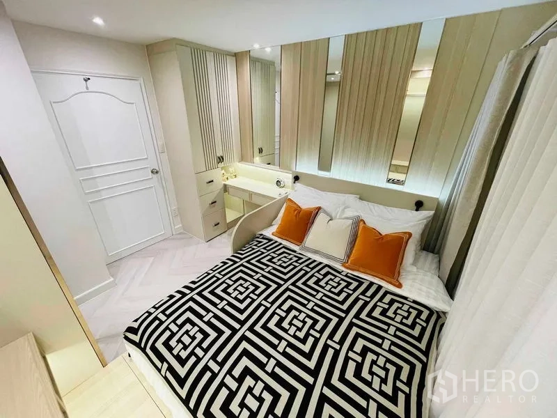 公寓 出售在Yan Nawa, Bangkok - 温馨卧室，黑白几何床品、橙色抱枕与内置梳妆台。