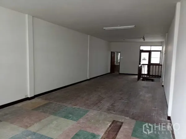 Shophouse for rent in Watthana, Bangkok - Large upper level open space with mixed flooring, doorway to a small room and open stairwell.