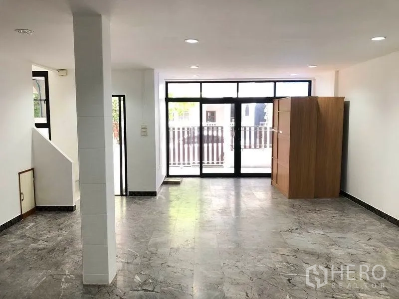 Townhouse for rent in Watthana, Bangkok - Open-plan living area with marble-look floors, recessed lighting and wide sliding glass doors to the front patio.