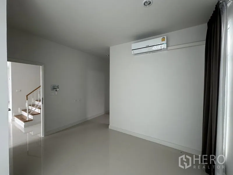 Detached House for sale in Lam Luk Ka, Pathum Thani - Compact room with air conditioner, white walls and blackout curtains.