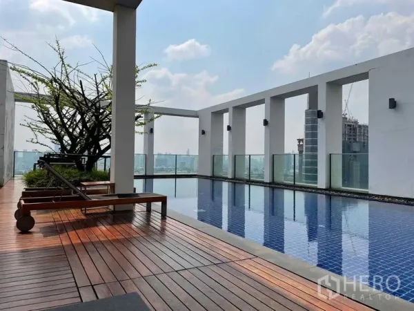 Condominium for sale in Phaya Thai, Bangkok - Rooftop swimming pool with wooden deck, city skyline views, and sun loungers near BTS Ari.