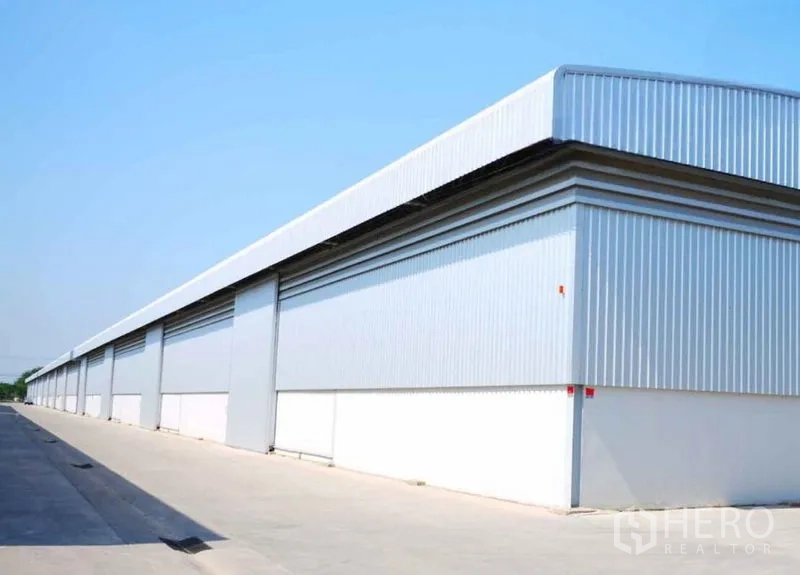 Warehouse for rent in Bang Sao Thong, Samut Prakan - Modern corrugated steel warehouse facade with long frontage and a clean concrete yard.