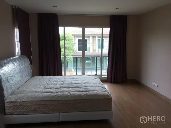 独立式住宅 出租在Pathum Thani - 宽敞主卧，木地板，落地阳台门与窗帘。