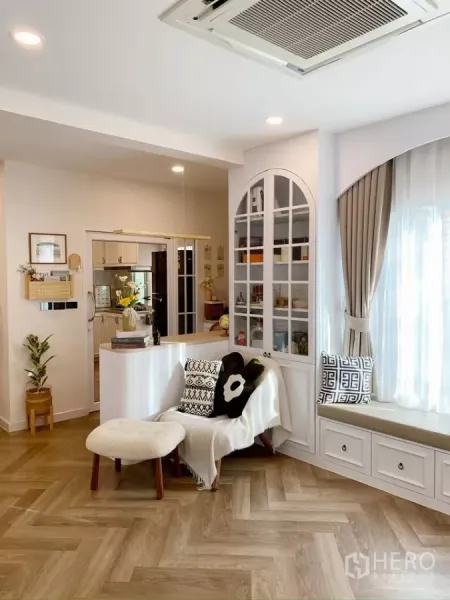 Detached House for sale in Sai Mai, Bangkok - Open-plan living area with window seat, glass cabinet and view toward the kitchen.