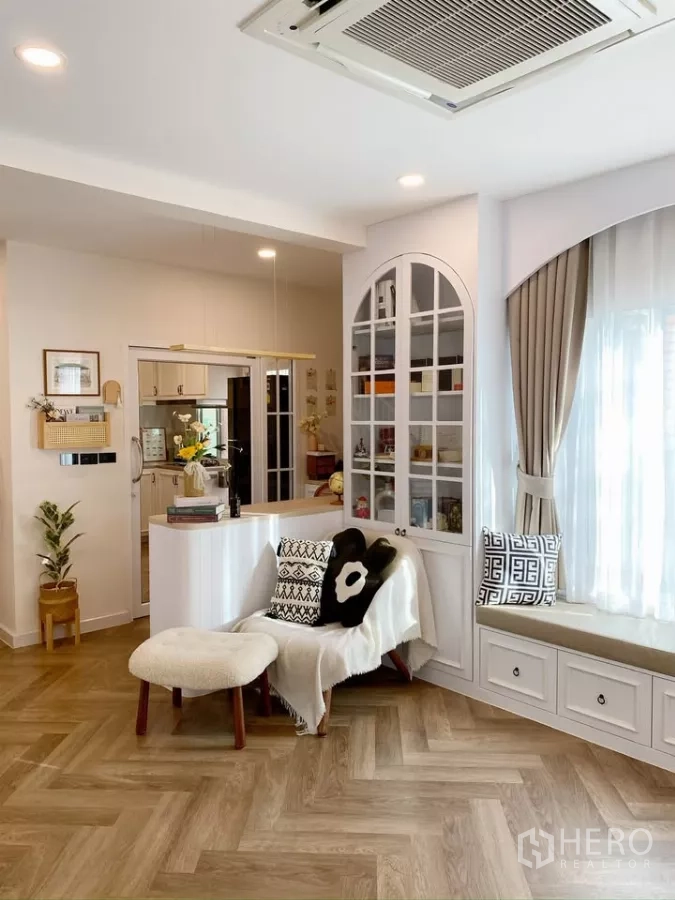 Detached House for sale in Sai Mai, Bangkok - Open-plan living area with window seat, glass cabinet and view toward the kitchen.