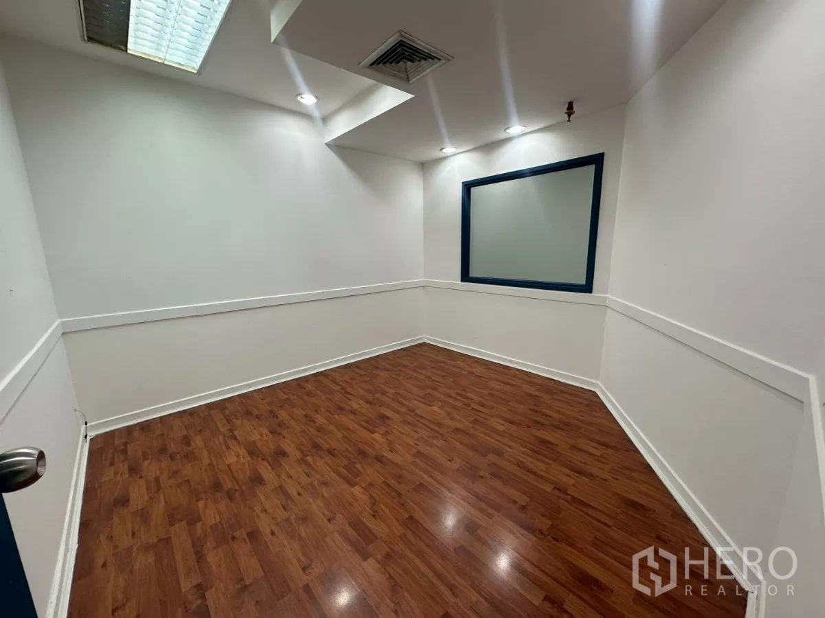 Office Space for rent in Khlong Toei, Bangkok - Small partitioned office room with wood flooring, recessed lights and an internal window.