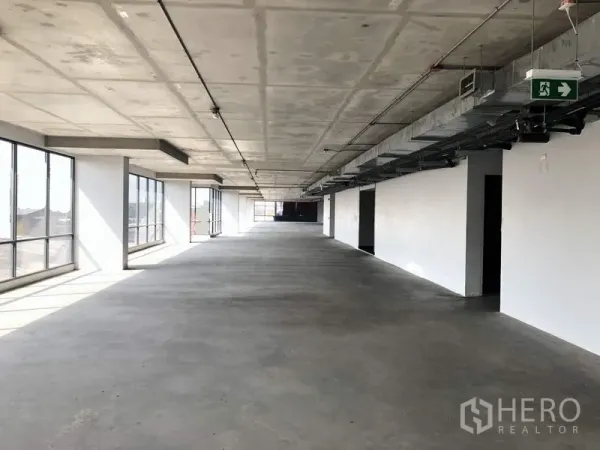 Office Space for rent in Suan Luang, Bangkok - Long open workspace with continuous window walls, exposed services, and an emergency exit sign.