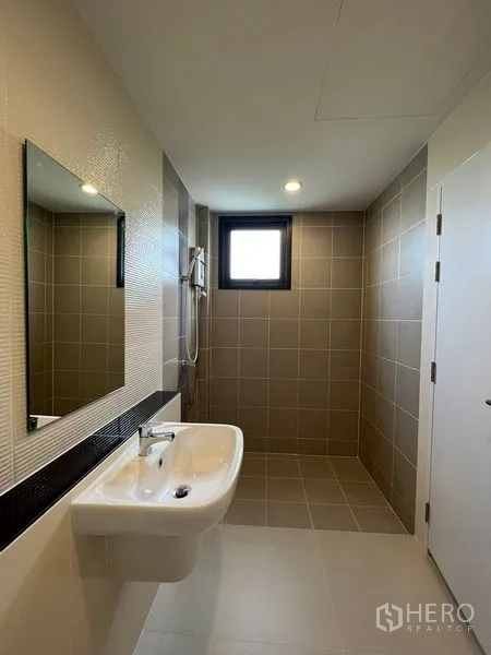 Detached House for rent in Saphan Sung, Bangkok - Bright bathroom featuring a walk-in shower, wall-mounted sink and a window for ventilation.
