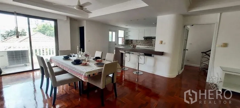 联排别墅 出租在Sathon, Bangkok - 明亮餐区，六人餐桌、吧台，以及通往阳台的推拉玻璃门。