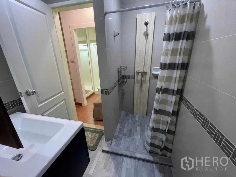 Condominium for rent - Bathroom with walk-in shower, tiled walls and vanity basin.