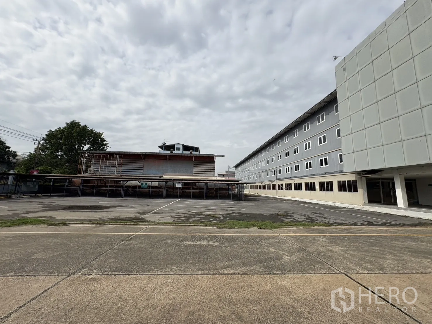โรงงาน ให้เช่าในPhra Pradaeng, Samut Prakan - ลานคอนกรีตกว้างและที่จอดรถข้างอาคารสำนักงานหลายชั้น