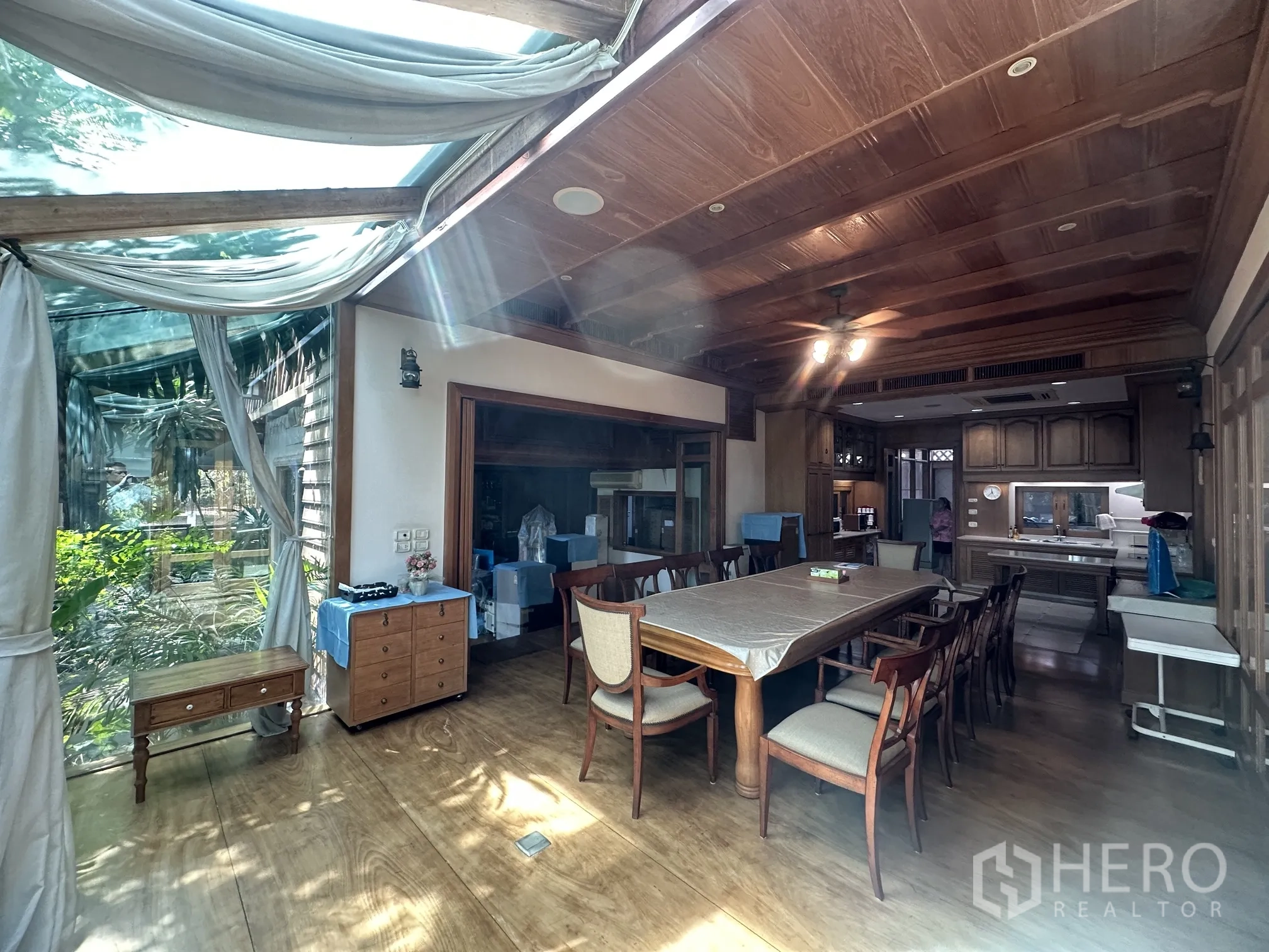 Detached House for rent in Lam Luk Ka, Pathum Thani - Garden-facing dining room under a glass roof with beams and a ceiling fan.