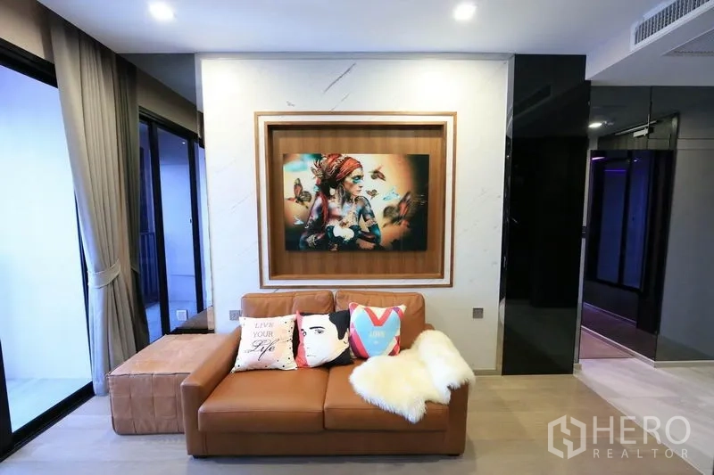 公寓 出租或出售在Watthana, Bangkok - 温馨小客厅，装饰画、阳台门与柔和灯光。