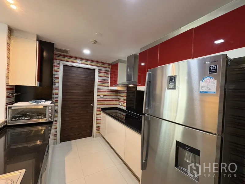 公寓 for rent in Khlong San, Bangkok - 现代厨房，红色橱柜、条纹墙面、黑色台面与不锈钢冰箱。