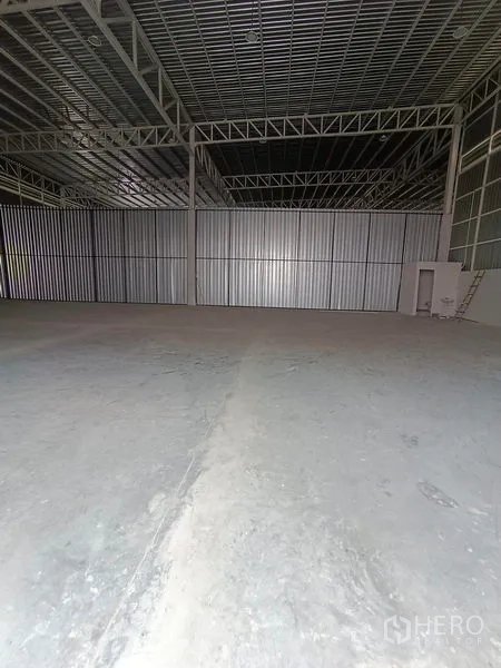 Warehouse for rent in Khlong Toei, Bangkok - Wide-span storage area with corrugated metal partition wall, service door and ladder.