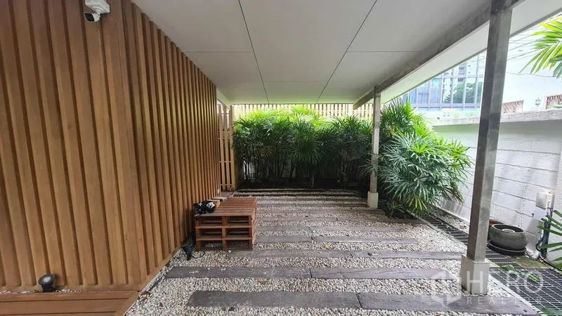 Detached House for rent in Watthana, Bangkok - Covered carport with slatted wood wall and pebble flooring.