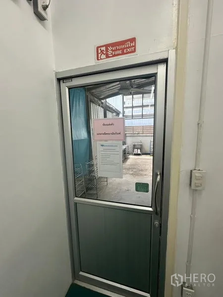 Warehouse for rent or sale in Lam Luk Ka, Pathum Thani - Fire exit door with signage leading to an exterior service area of the warehouse.