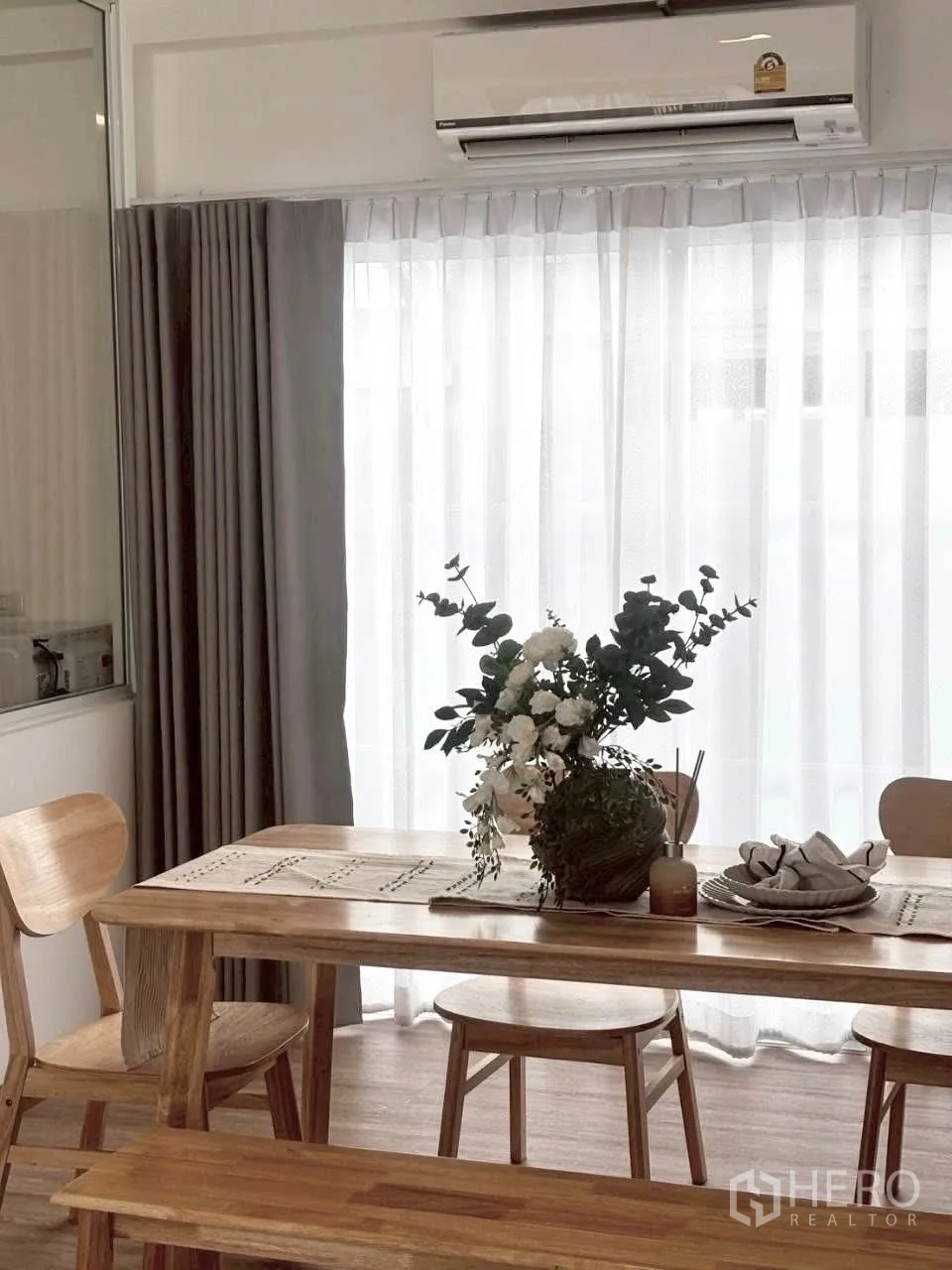 联排别墅 for rent in Prawet, Bangkok - 用餐区配木质餐桌椅与花艺，墙挂空调上方送风。