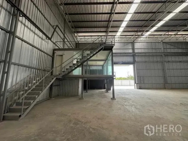 Factory for rent in Wang Noi, Phra Nakhon Si Ayutthaya - Spacious warehouse interior with high ceiling, skylight strips, and a mezzanine glass office accessed by steel stairs.