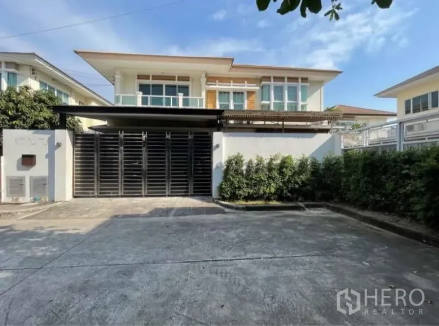 Detached House for rent in Bang Phli, Samut Prakan - Front facade with gated driveway, covered carport and modern windows.
