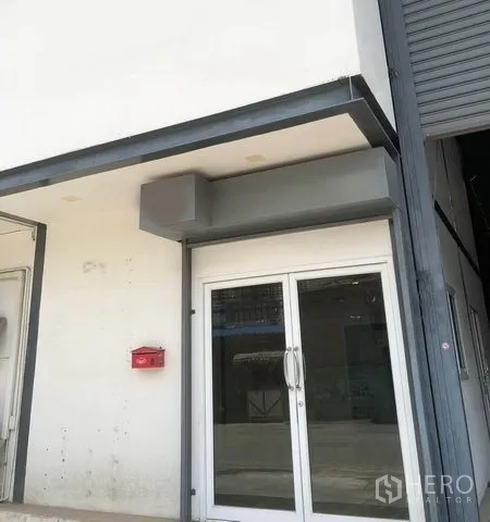 货栈 出租在Pak Kret, Nonthaburi - 建筑入口，双扇玻璃门与大型卷闸门。