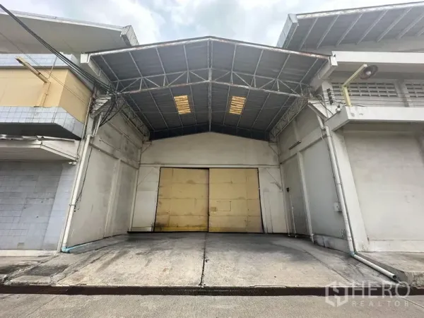 Warehouse for rent in Yan Nawa, Bangkok - Front facade of the warehouse with ramped driveway and double sliding doors.